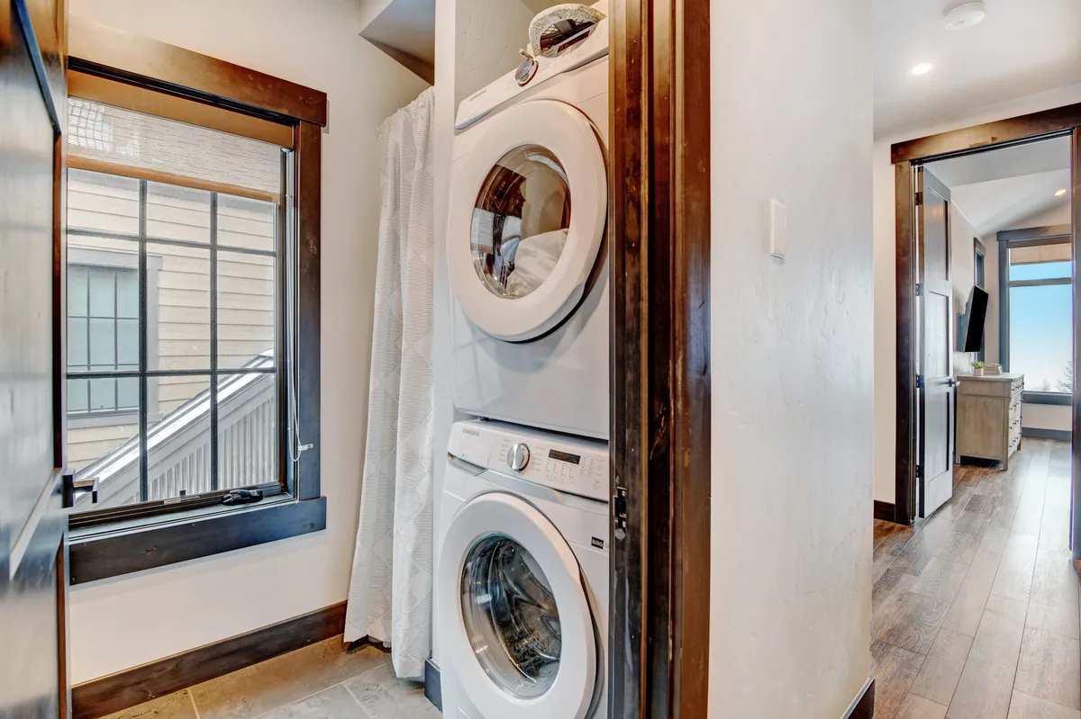 A practical and inviting laundry area featuring a stacked washer and dryer next to a window with views to the outside, underscoring the convenience of extended-stay amenities in a home-like setting.