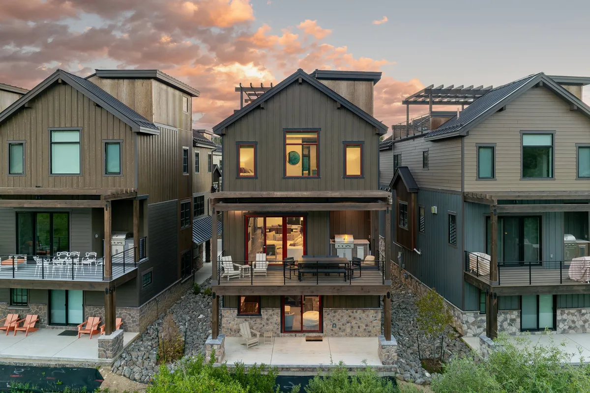 This image features the villa's modern exterior with outdoor seating and large windows, hinting at inviting communal spaces inside. The open balcony area suggests opportunities for group gatherings and relaxation while enjoying the surrounding views, making it ideal for multi-generational families or groups.