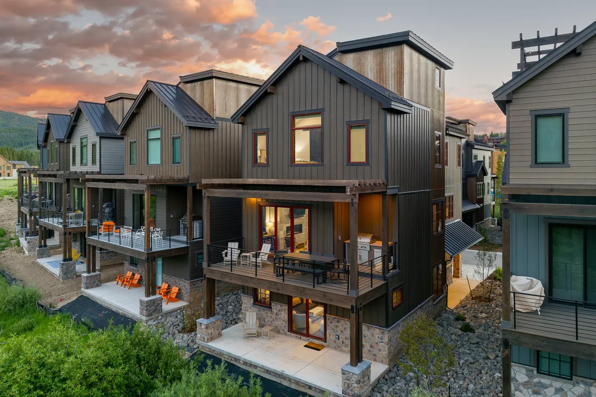Modern architecture with a spacious deck featuring outdoor seating and mountain views. The setting is perfect for group outdoor dining, relaxing, or enjoying post-activity downtime together, surrounded by landscaped greenery.