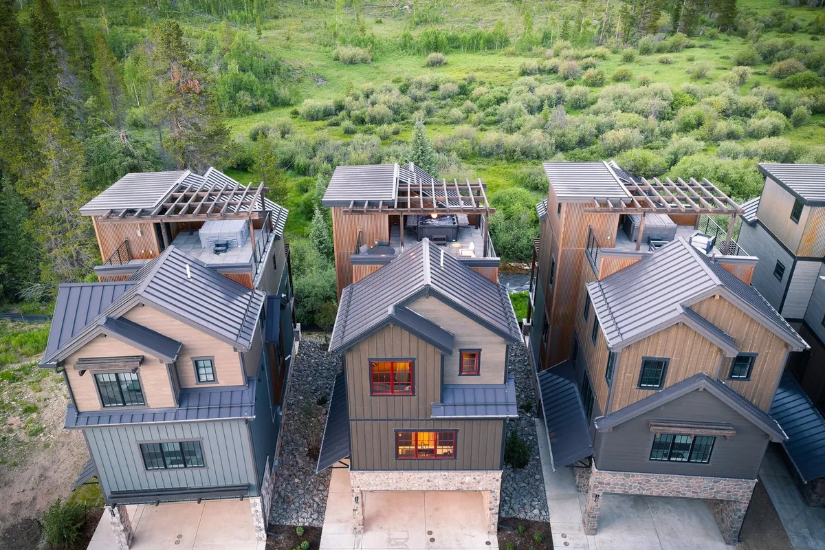 This exterior scene shows a row of modern homes set against a backdrop of green landscaping and open sky. The community feels welcoming and provides an inviting first impression, hinting at the outdoor spaces that pets and owners can explore together. The visible greenery and spacious layout connect directly to the idea of dog-friendly escapes.