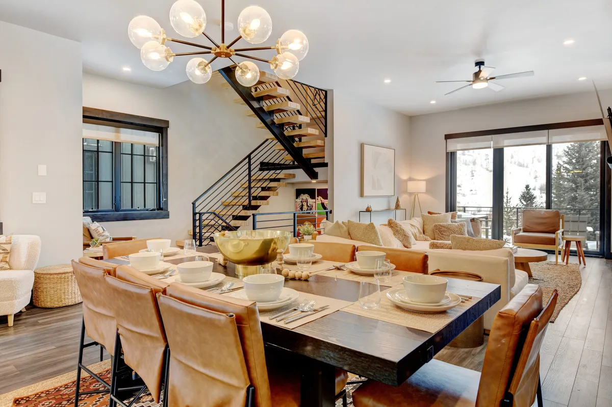 A welcoming dining area with a large wooden table, comfortable chairs, a view of the sofa area, and expansive windows that flood the space with natural light. The layout is ideal for shared meals and lively conversations.