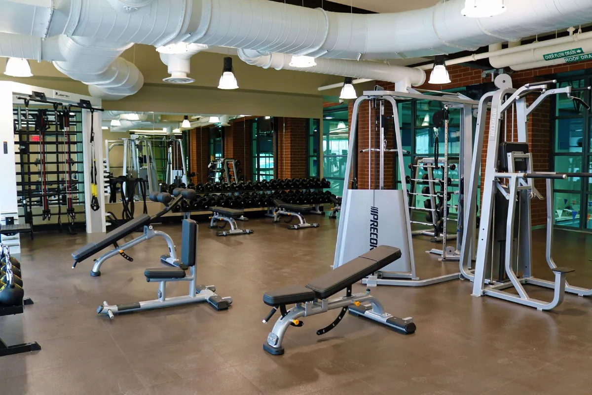 A well-equipped fitness center featuring weightlifting equipment, exercise benches, and mirrored walls, designed for personal or group workouts in a motivating environment.